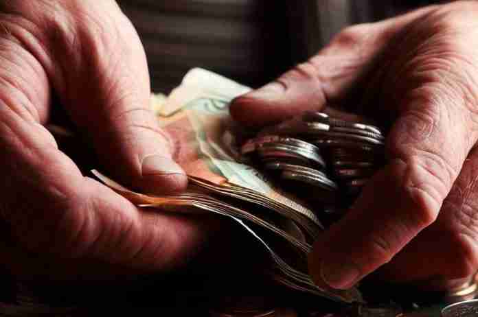 Pensionato che conta i soldi della pensione e supplemento